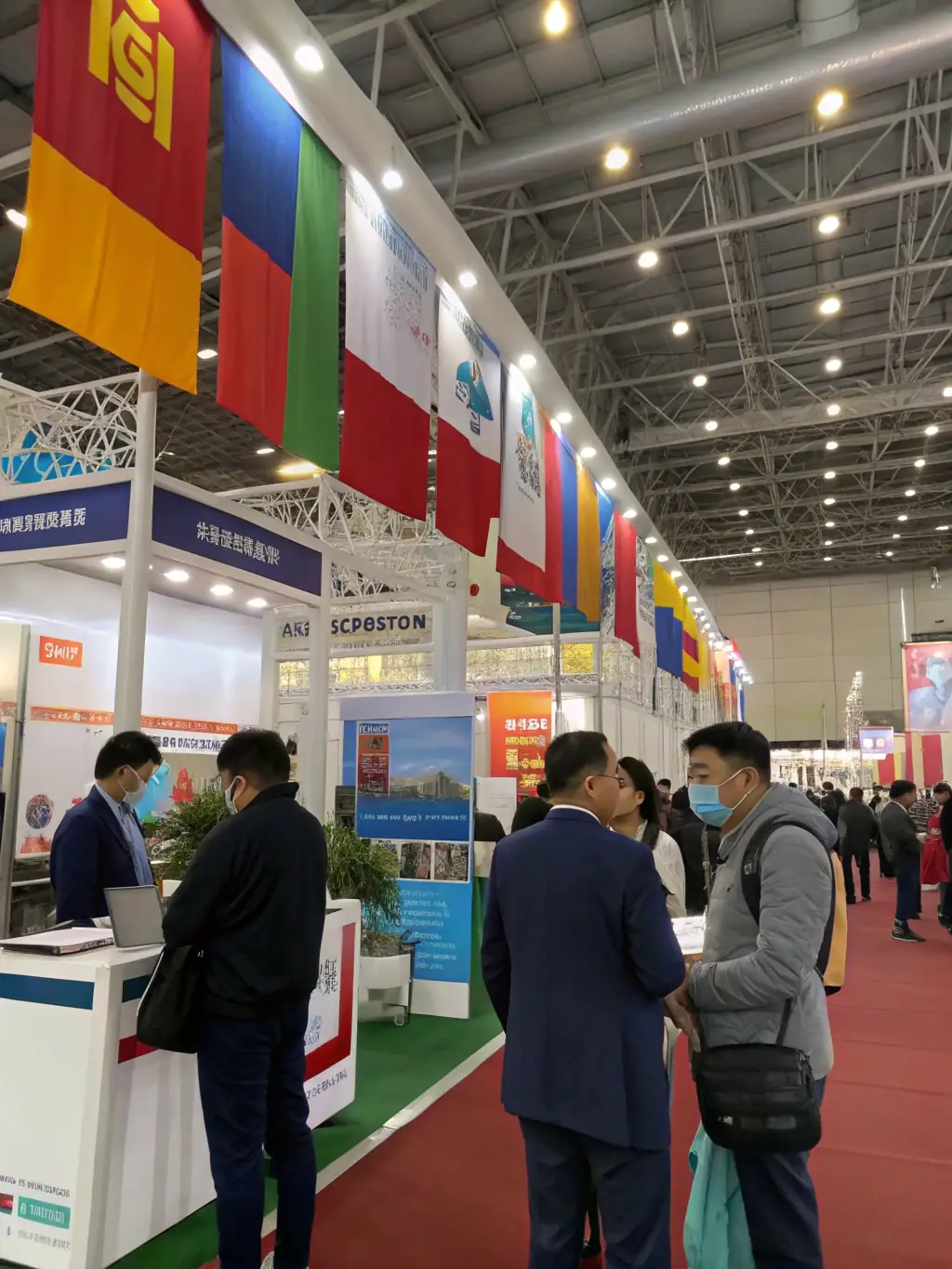 A photograph of the exhibition area at a UK Industry Summit, featuring sponsor booths and attendees exploring the latest products and services.